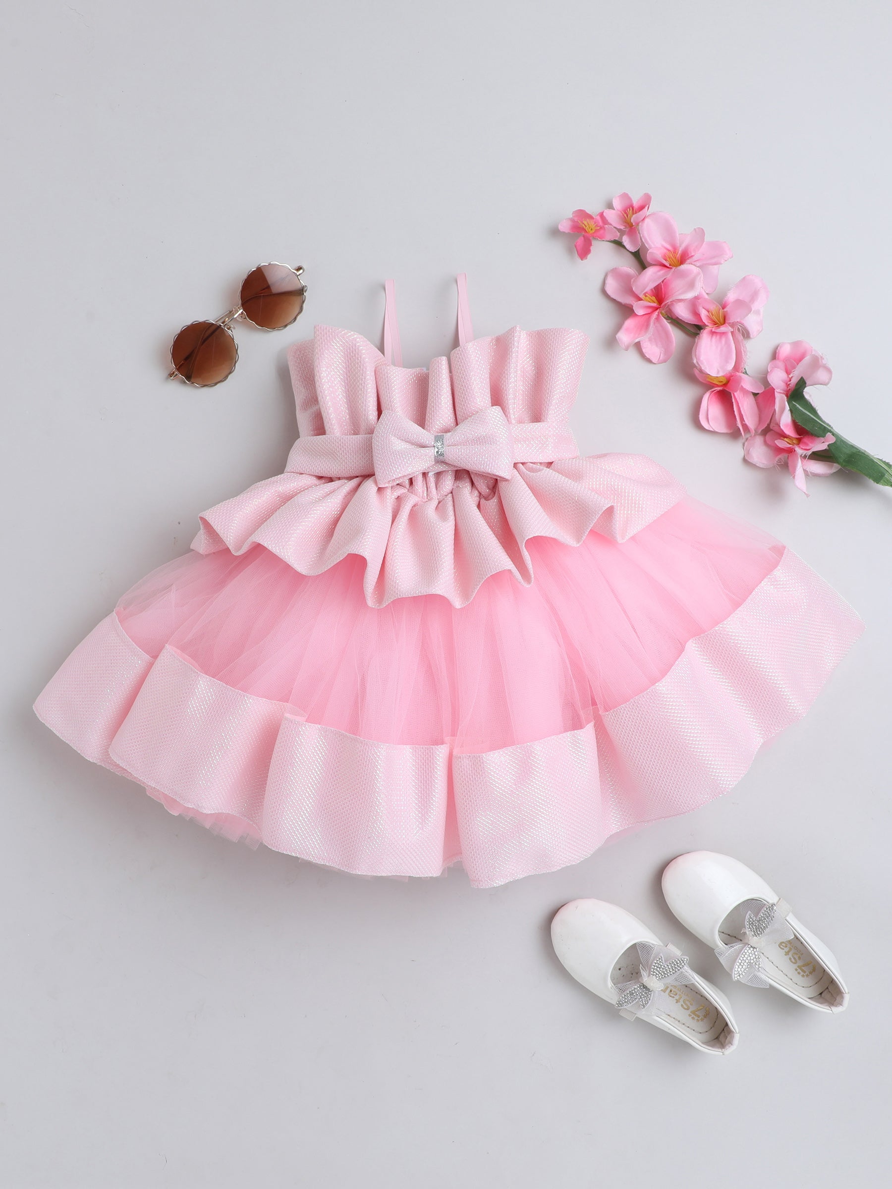 "Dreamy tutu gown featuring a shimmery bow belt, layered ruffles, and delicate straps – perfect for birthdays,